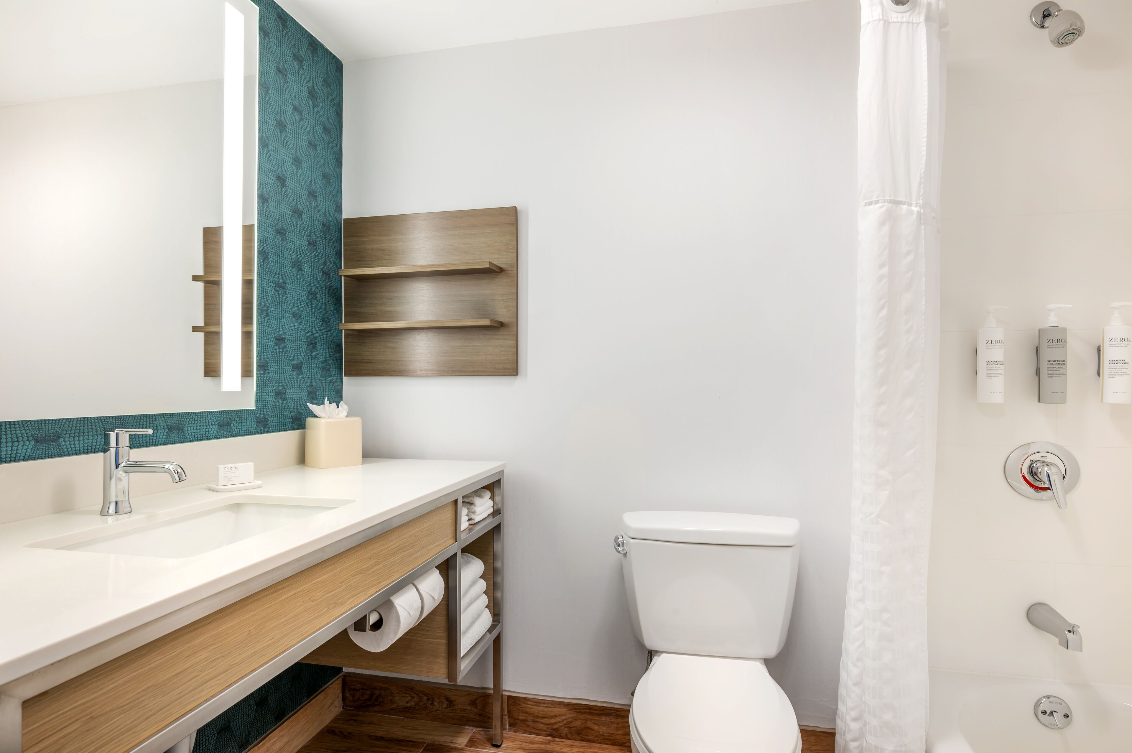 Un baño moderno con un lavamanos blanco, un espejo, un inodoro y una cortina de ducha.