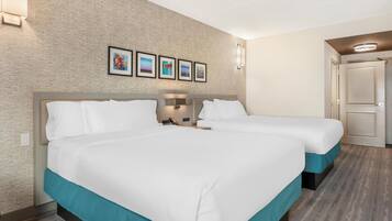 A hotel room with two beds, a brick-patterned wall, and framed artwork above the beds.
