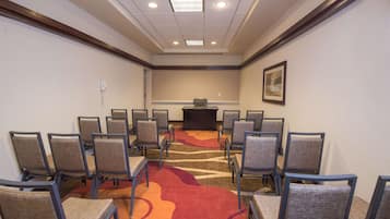 Een congreszaal met rijen stoelen, een spreekgestoelte en een vloerbedekking.