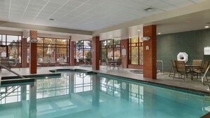 An indoor swimming pool with clear water, surrounded by brick pillars and large windows. - Hilton Garden Inn Wisconsin Dells (Wisconsin Dells)