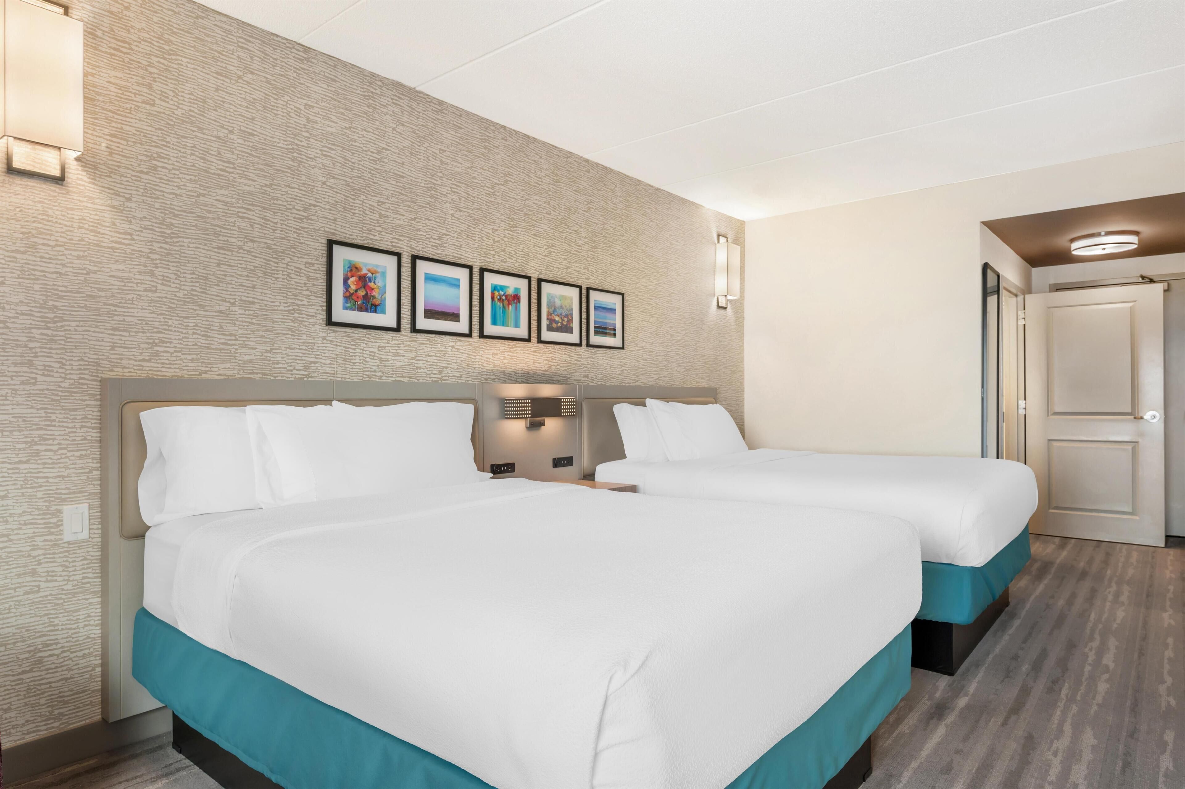 Une chambre d’hôtel avec deux lits, un mur décoré d’un motif en briques et des tableaux encadrés.