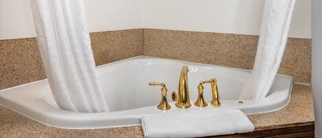 A bathroom with a freestanding bathtub, a shower curtain, and toiletries on the wall.