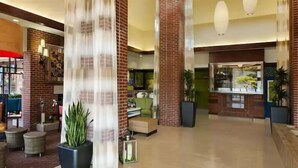 A spacious lobby with high ceilings, brick walls, and a modern chandelier. There are potted plants and a seating area with ottomans. - Hilton Garden Inn Wisconsin Dells (Wisconsin Dells)
