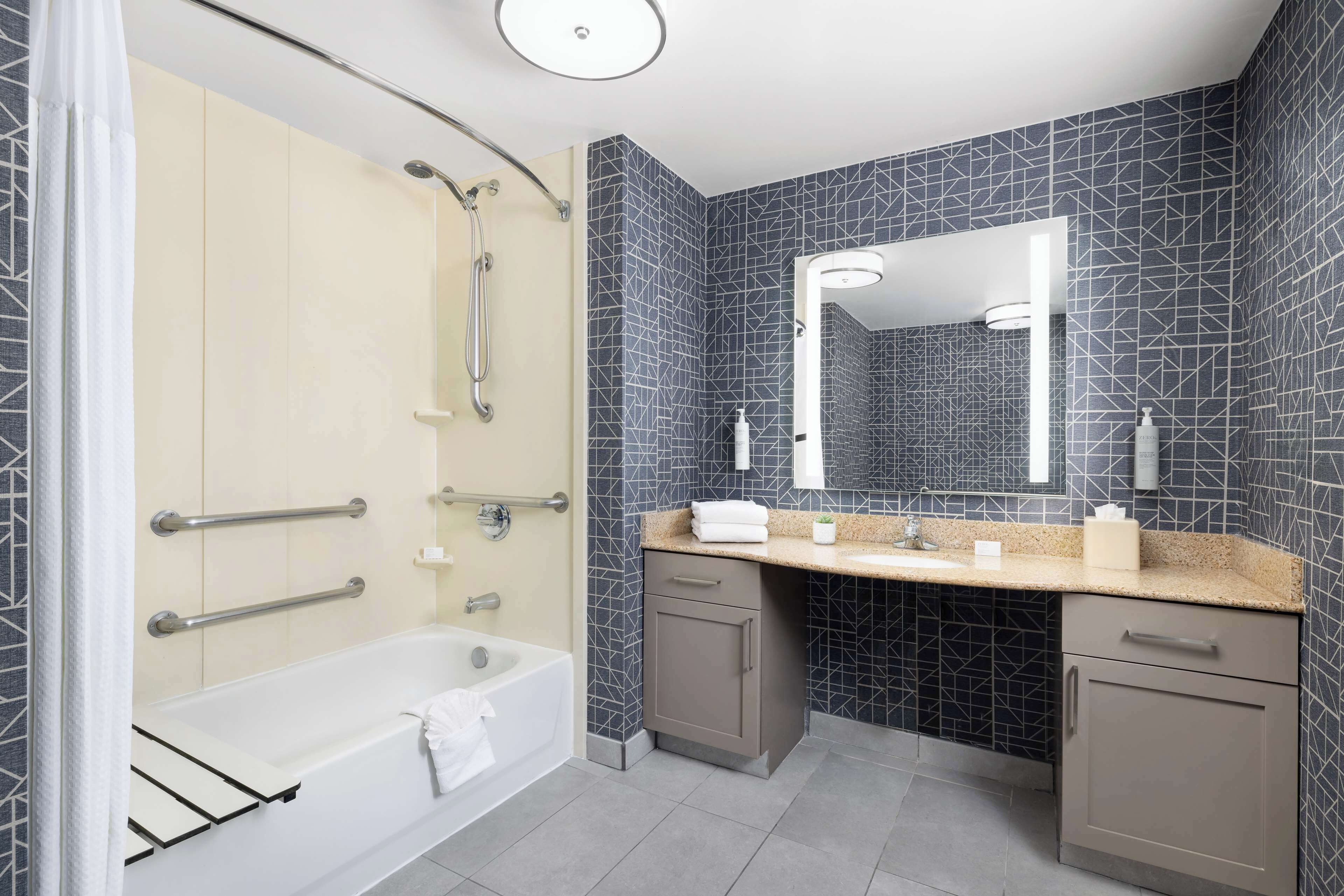 A modern bathroom with a bathtub, shower, and vanity with a mirror.
