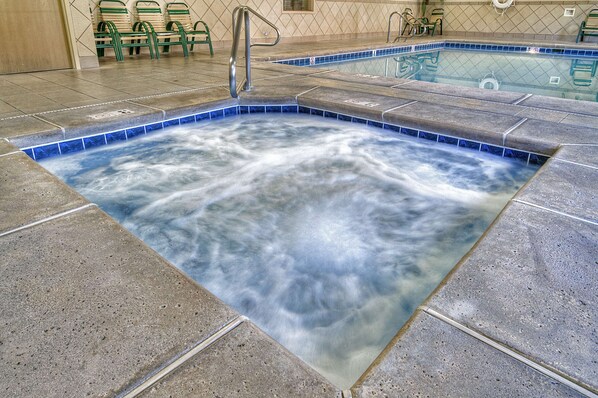 A hot tub with a tiled edge and a metal handrail.