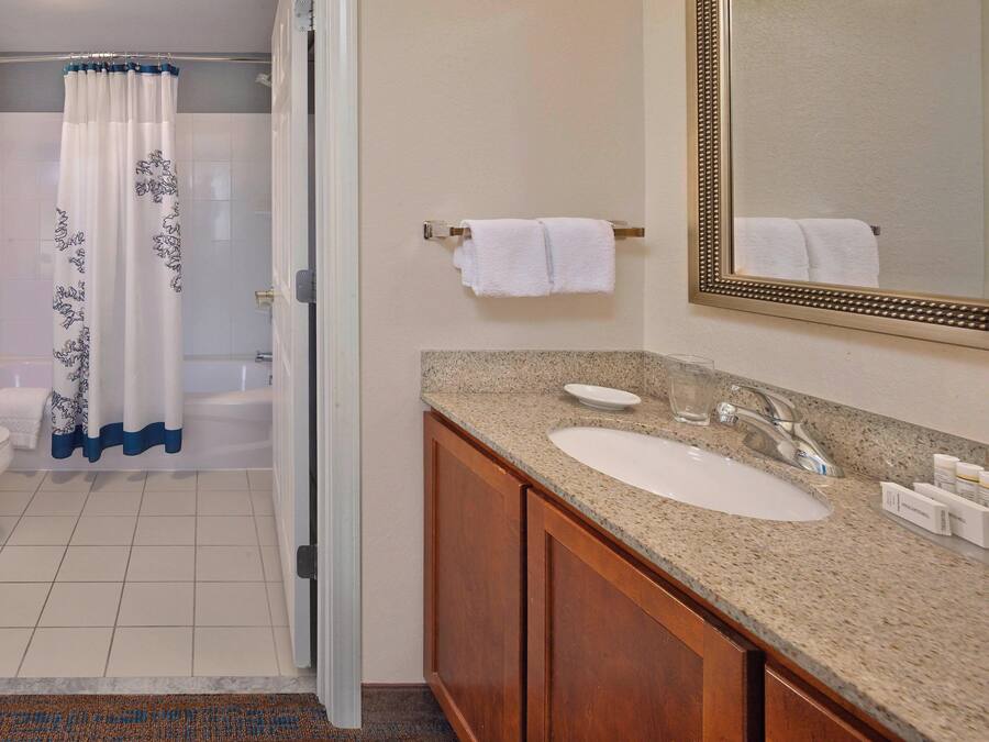 A bathroom with a shower, toilet, sink, and mirror.