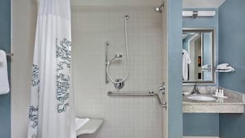 Un baño con ducha, lavamanos y espejo.