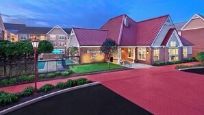 Un hôtel Marriott avec un toit rouge, une piscine et une pelouse bien entretenue.