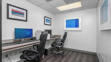 A modern office with a desk, computer, and two chairs.