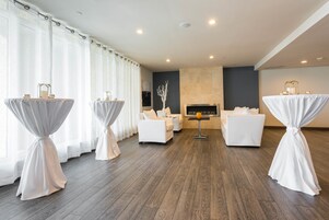 Una habitación amplia con chimenea, muebles blancos y mesas con manteles blancos.
