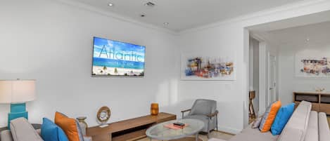 A modern living room with a sofa, armchairs, a coffee table, and a TV displaying 'The Atlantic Hotel & Spa'.