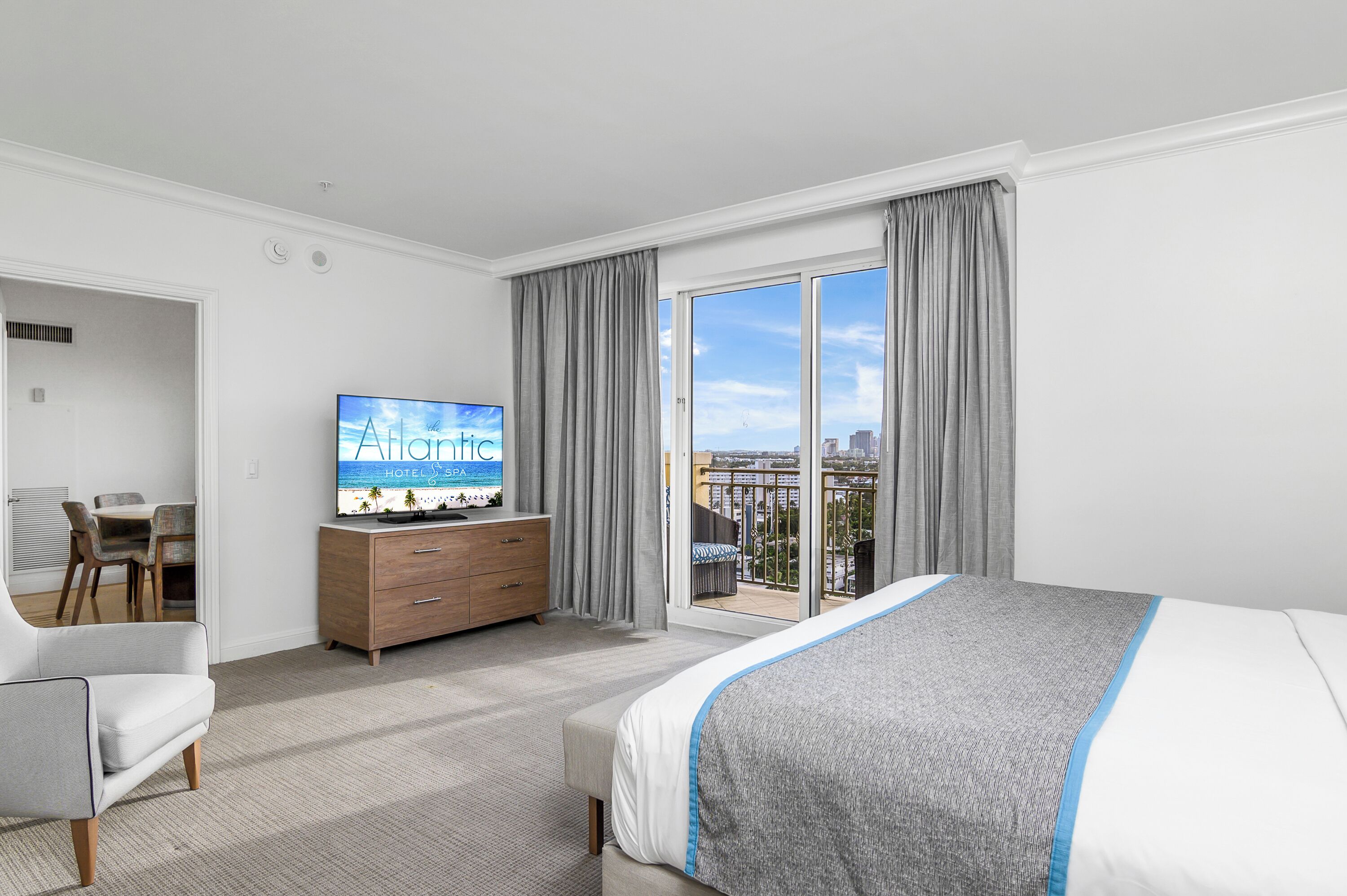 Une chambre d’hôtel équipée d’un lit, d’une télévision, d’un bureau et offrant une vue sur la ville grâce à de grandes fenêtres.