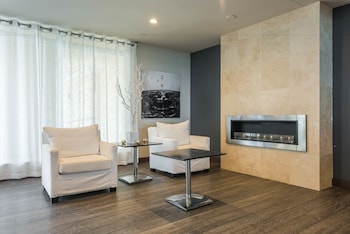 A modern kitchen with a black countertop, stainless steel appliances, and white cabinetry. There is a dining area with a table and chairs, and a view of the balcony through the open door. at The Atlantic Hotel & Spa
