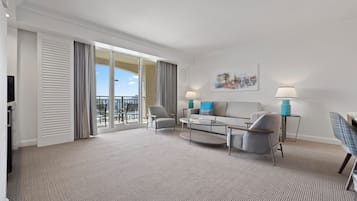 Ein modernes Hotelzimmer mit großem Balkon, einer Sofagruppe, einem Couchtisch und zwei Lampen.
