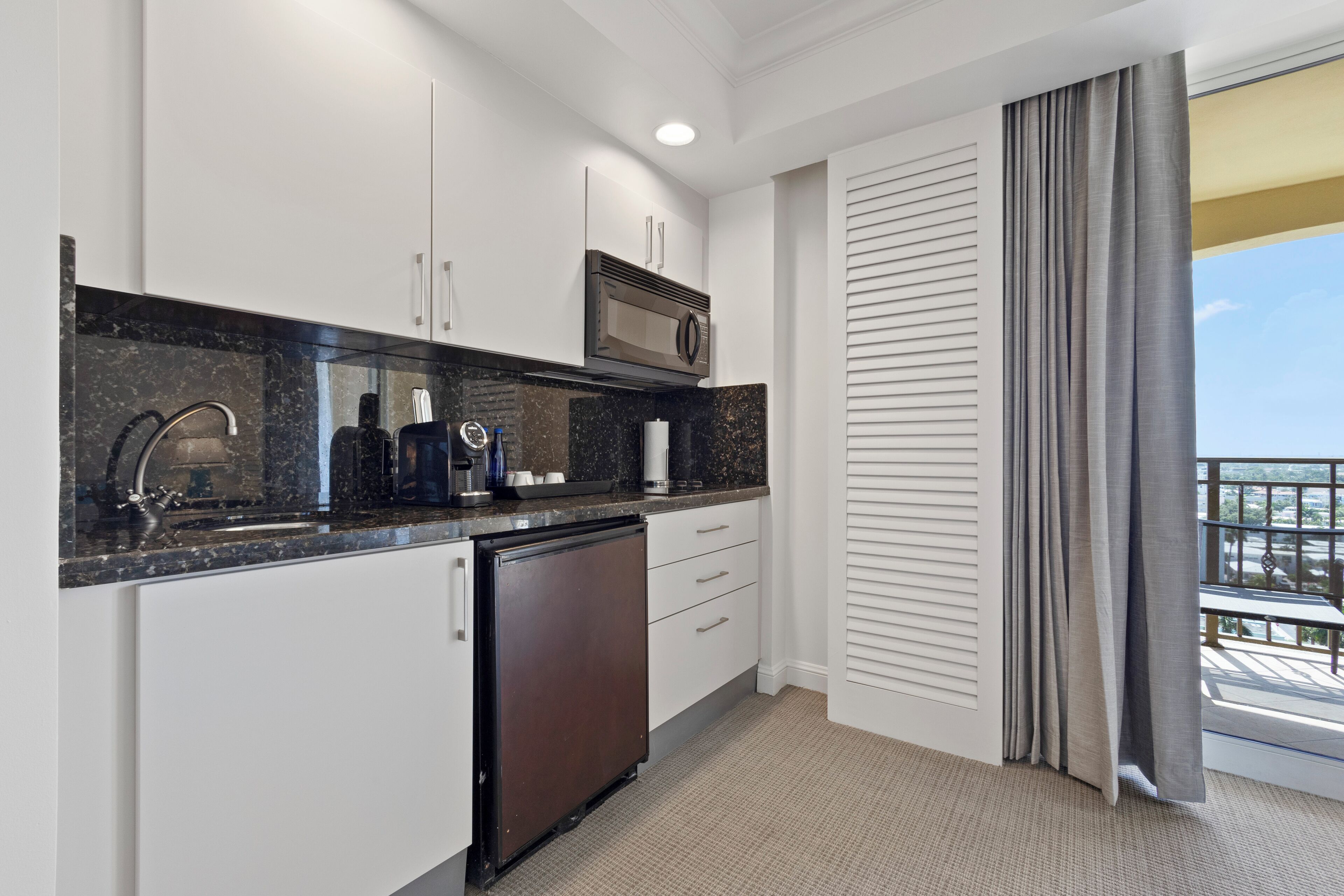 A modern kitchen with white cabinets, a black countertop, a microwave, and a dishwasher.