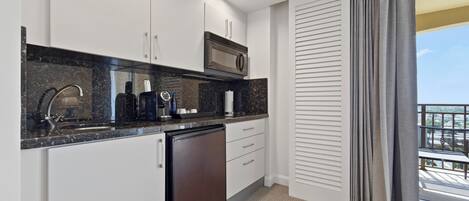 A modern kitchen with white cabinets, a black countertop, a microwave, and a dishwasher.