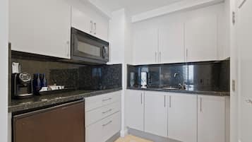 Una cocina moderna con armarios blancos, una encimera de granito negro y un microondas integrado.