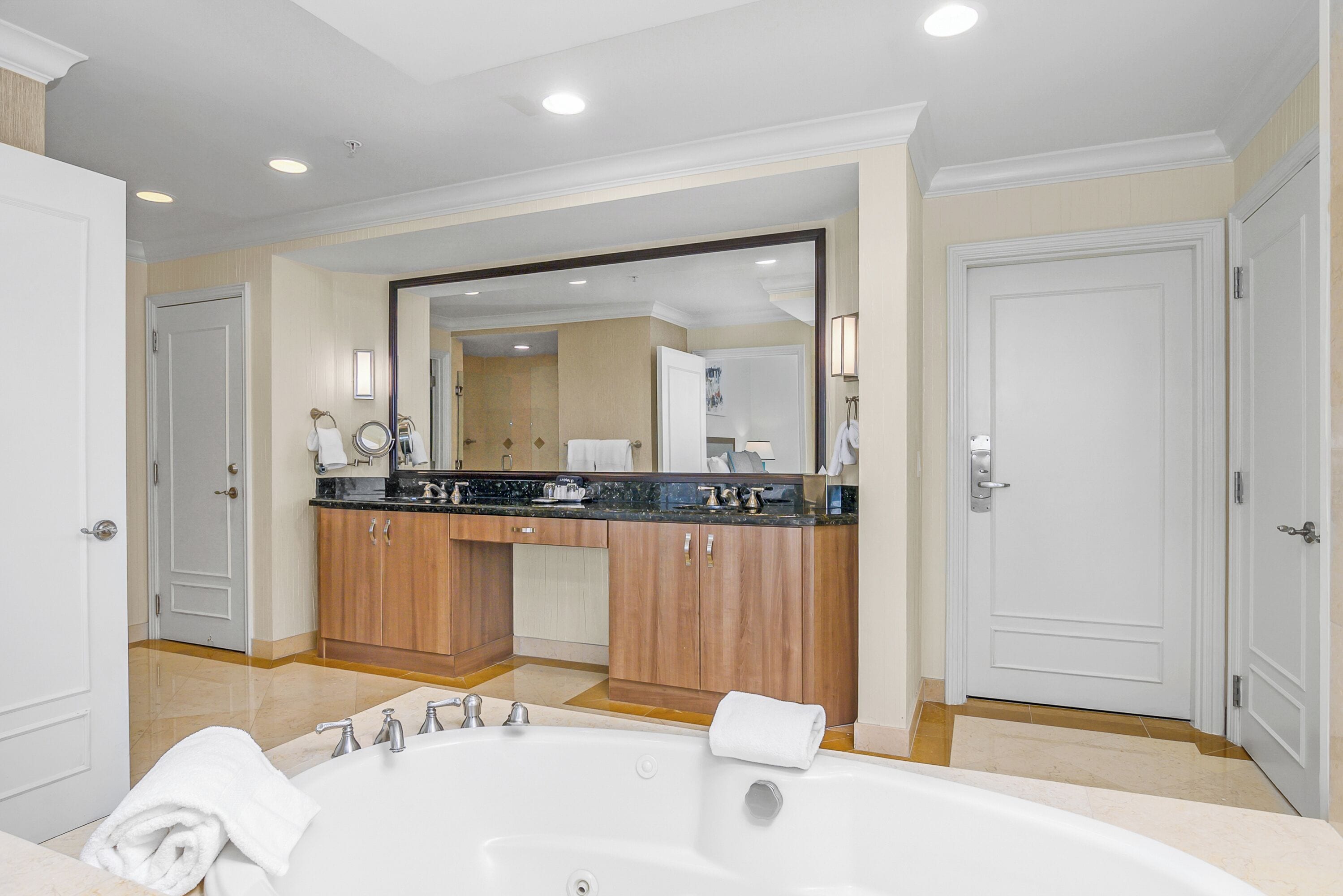 A modern bathroom with a large bathtub, wooden cabinets, and a mirror above the sink.