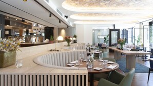 Un restaurante moderno con techo alto que presenta un diseño floral, muebles de madera y una zona de bar al fondo.