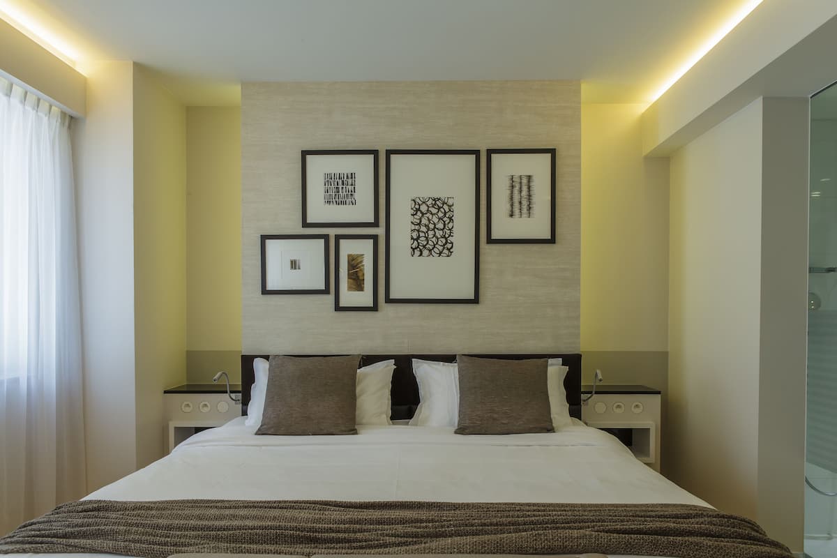Een moderne hotelkamer met een groot bed, een nachtkastje, een wandtelevisie en een kunstwerk in een lijst.