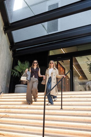 Deux personnes descendent un escalier extérieur, avec un bâtiment moderne en arrière-plan.
