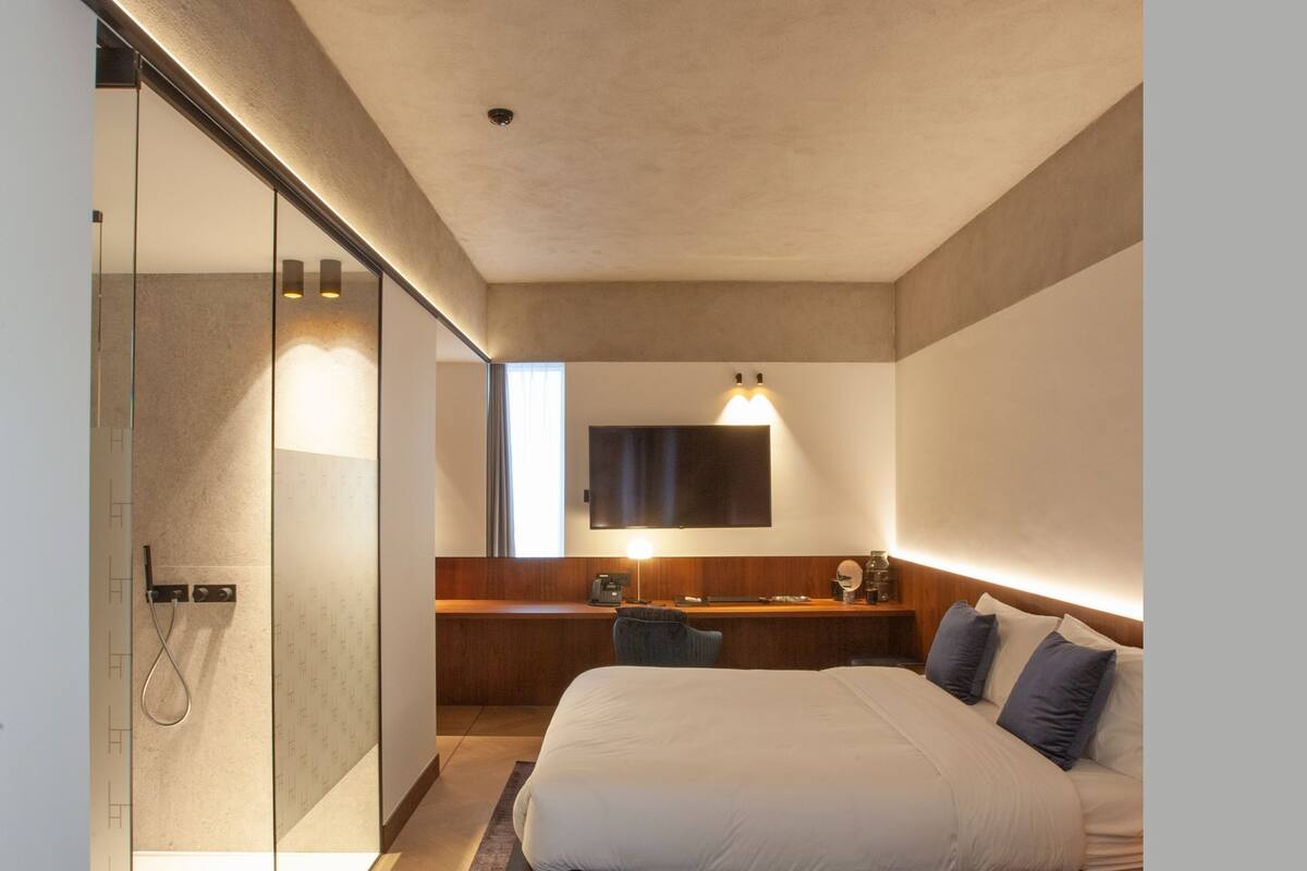 Een moderne hotelkamer met een groot bed, een bureau en een douche.