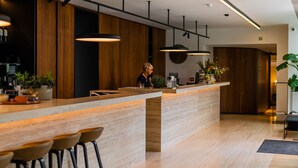 Una cocina moderna con barra de madera, iluminación colgante y una persona de pie junto al mostrador.