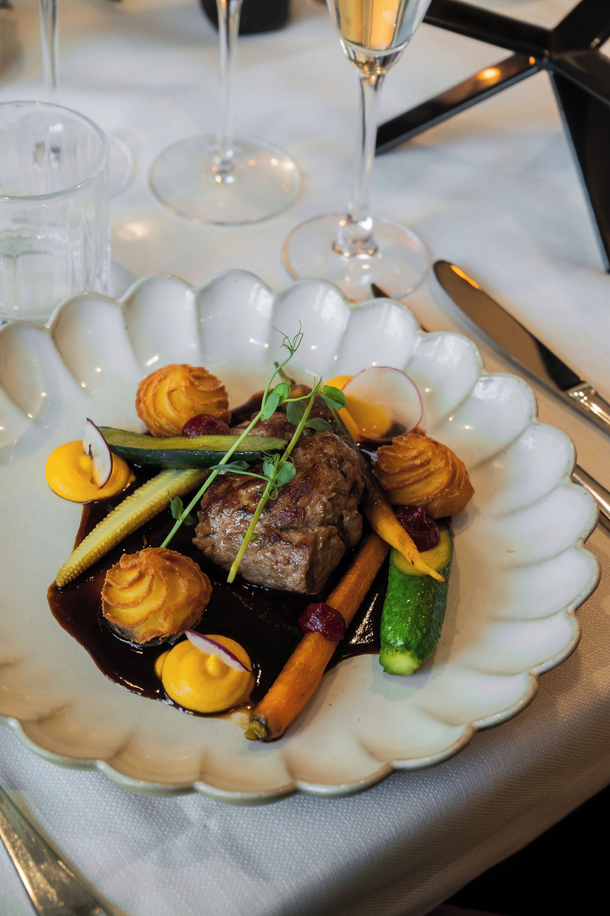 Ein Teller Essen mit gewölbtem Rand, ein Messer und ein Glas.