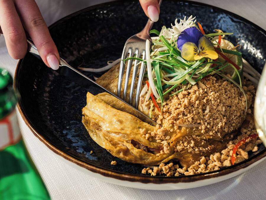 Iemand snijdt een gerecht aan met een vork en mes.