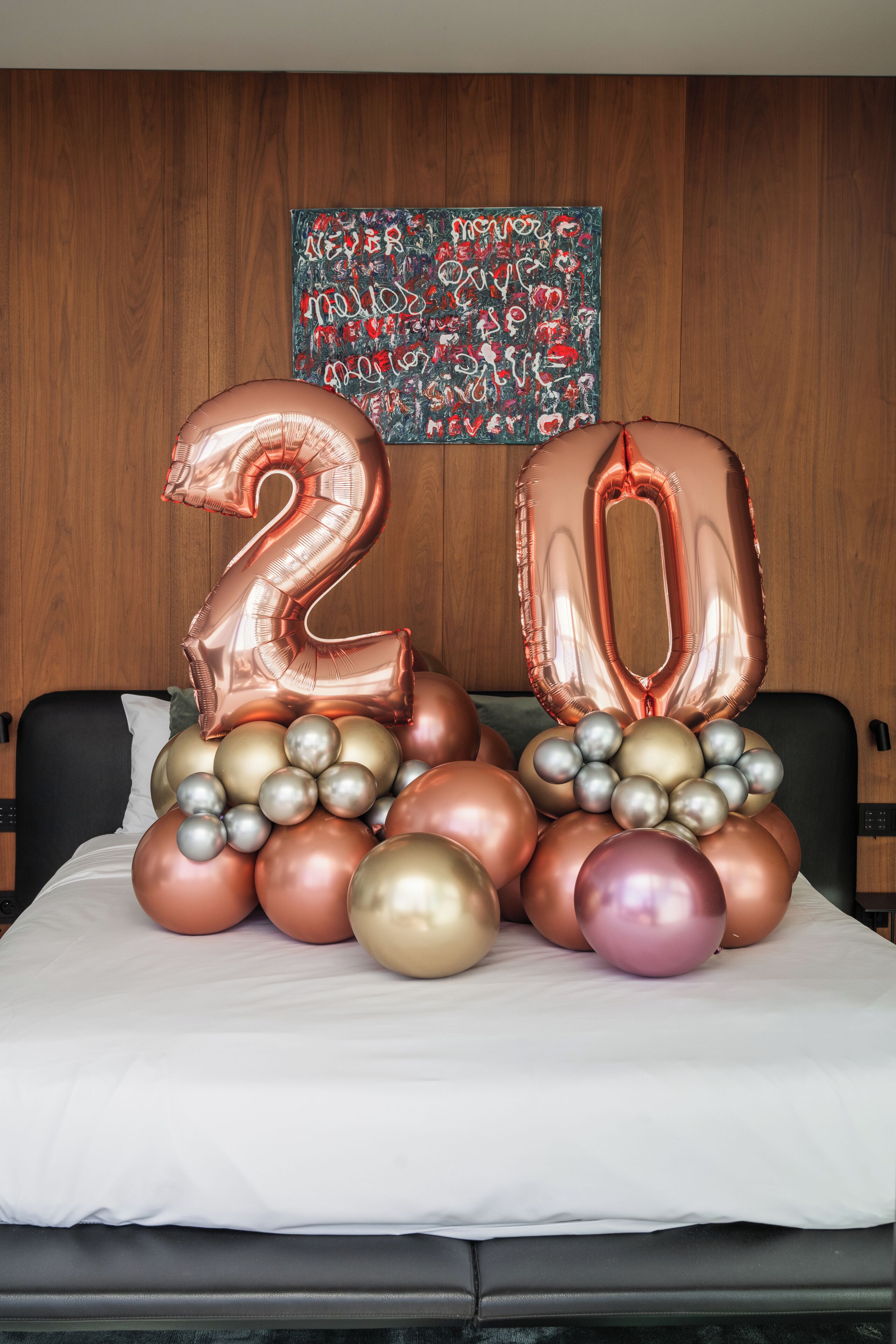 Ein Bett mit einer dekorativen Ballon-Anordnung, darunter ein Ballon mit der Zahl 20.