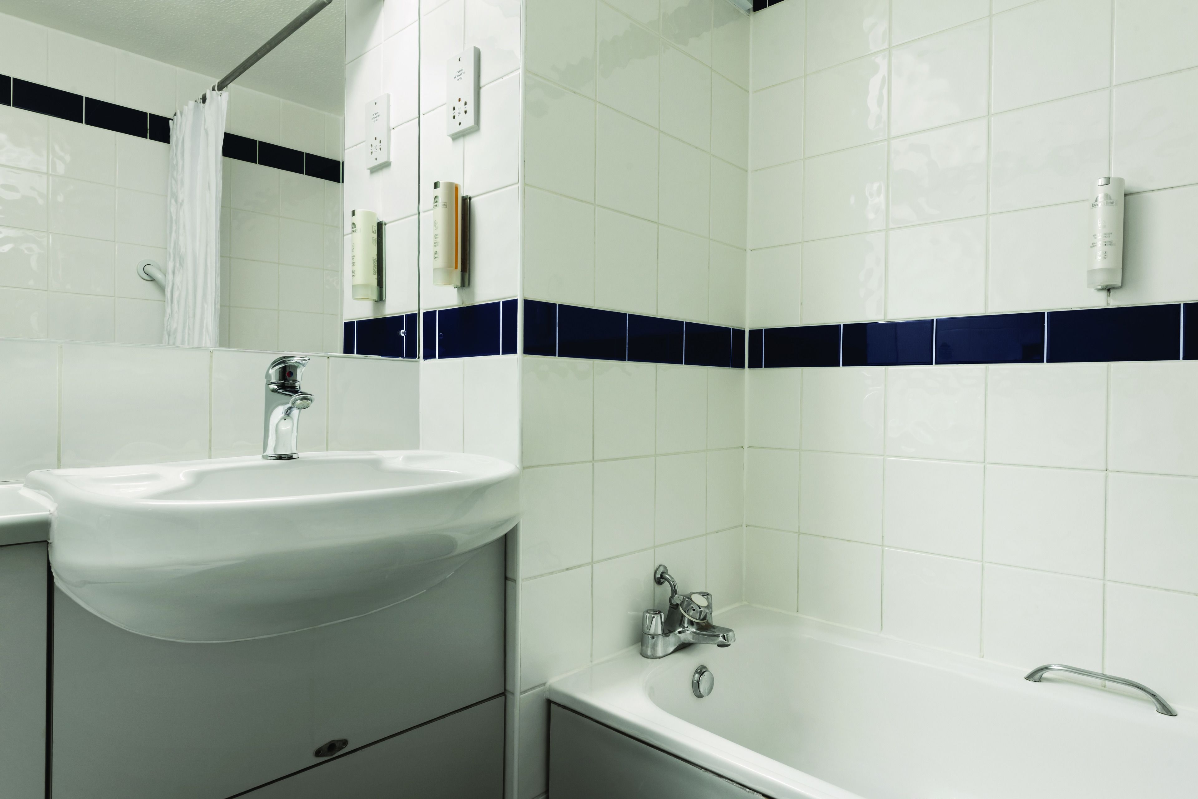 Une salle de bain avec un lavabo, un miroir et une baignoire.