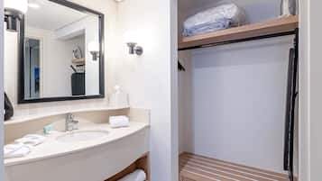 A bathroom with a sink, mirror, and shelves with toiletries.