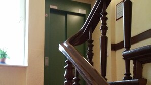 A staircase with wooden balusters and a red carpeted landing. - Hotel Abendstern (Berlin)