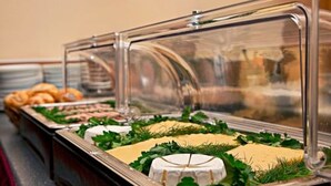 A buffet with various food items, including cheese and pastries, displayed in clear glass covers. - Hotel Abendstern (Berlin)