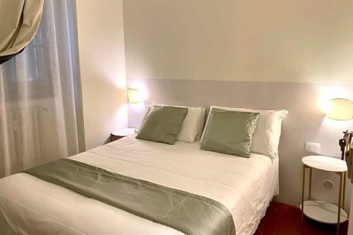 A hotel room with a bed, two bedside tables, and a nightstand.