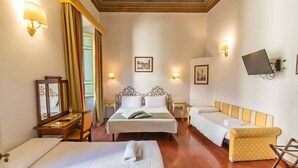 A hotel room with two beds, a sofa, a TV, and a mirror. - Hotel Cimabue (Florence)