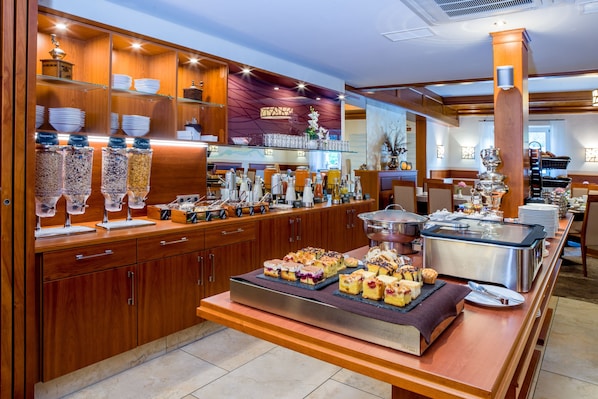 A buffet setup with various food items, a coffee station, and a display of glassware and china.