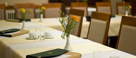 Une salle de conférence avec des tables disposées pour les réunions, agrémentée de vases avec des fleurs et de documents.