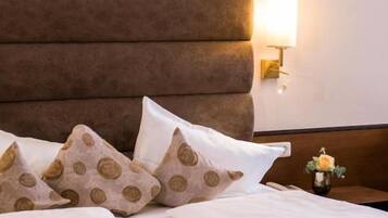 A neatly made bed with a headboard, pillows, and a bedside table with a lamp.