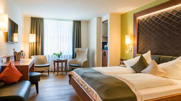 A hotel room with a bed, a desk, a chair, a small table, and a sofa.