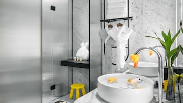 Un baño moderno con lavamanos de mármol, un taburete amarillo y una bata blanca.