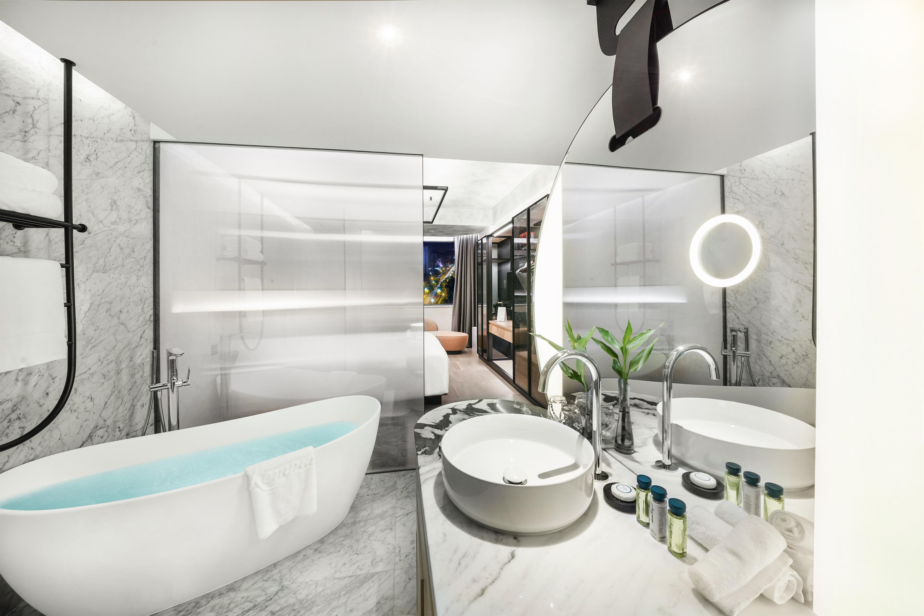 Une salle de bain moderne avec une baignoire sur pieds, un meuble-lavabo doté d’un grand miroir et un espace douche.