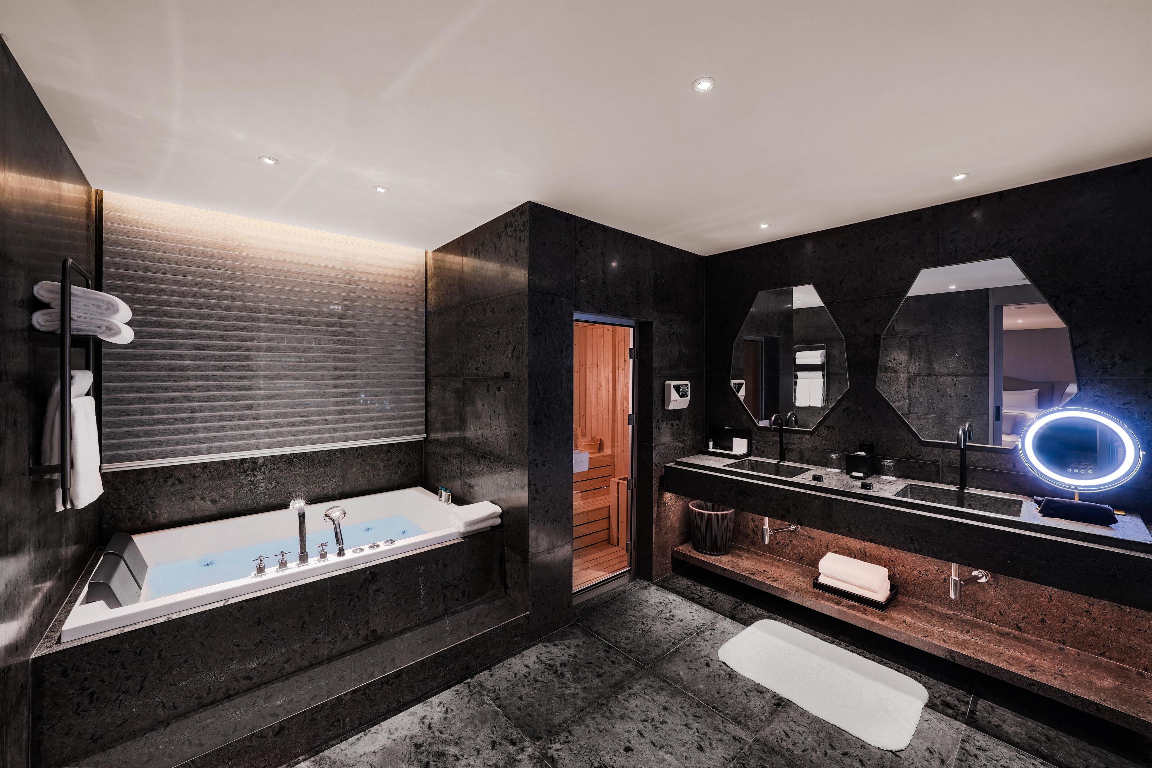 A modern bathroom with a freestanding bathtub, a large mirror with a ring light, and a vanity with a sink and towel rack.