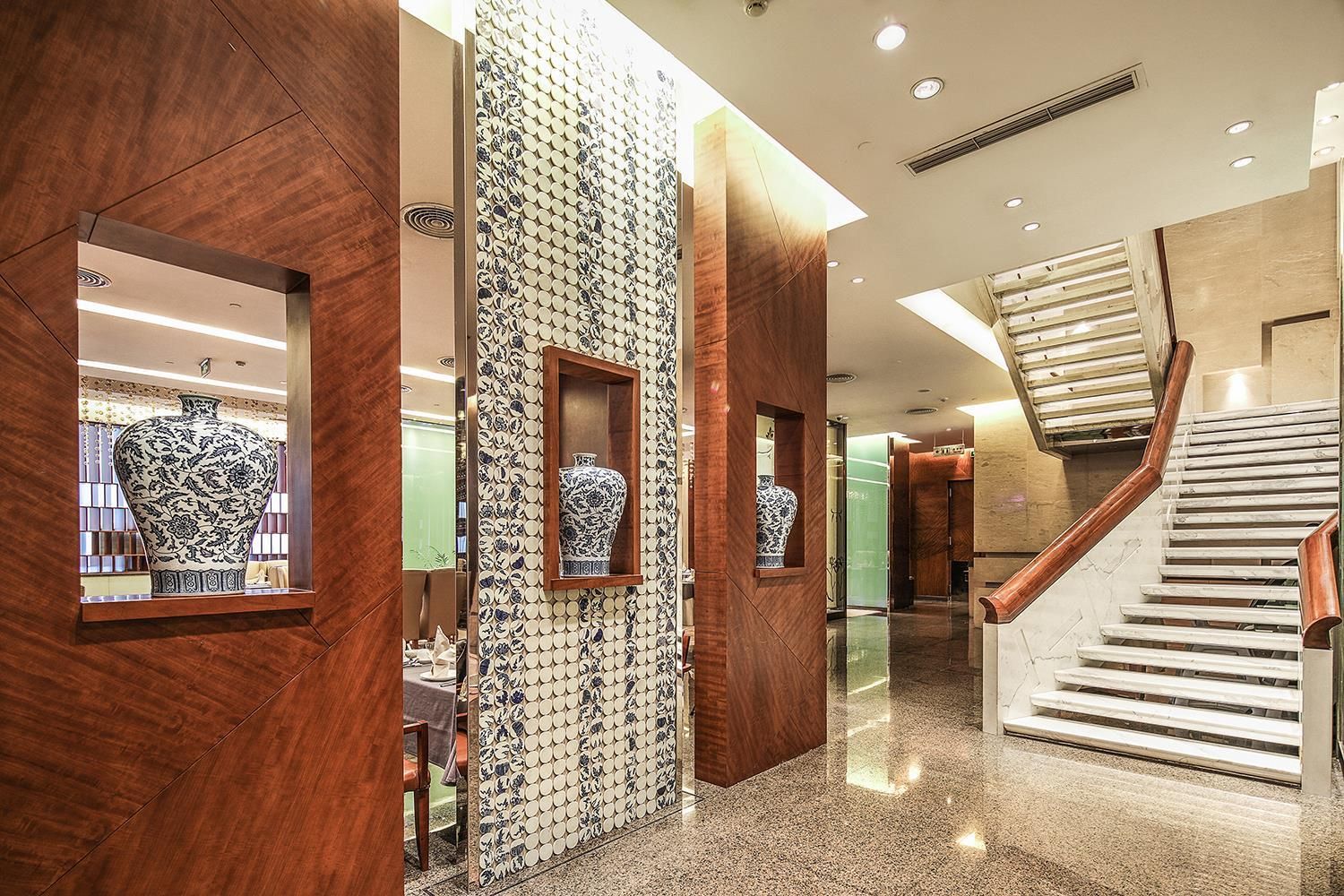 A modern interior with a wooden reception desk, a patterned wall, and a staircase.