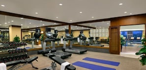 Une salle de sport équipée de tapis de course, d’haltères et de tapis de sol pour les exercices.