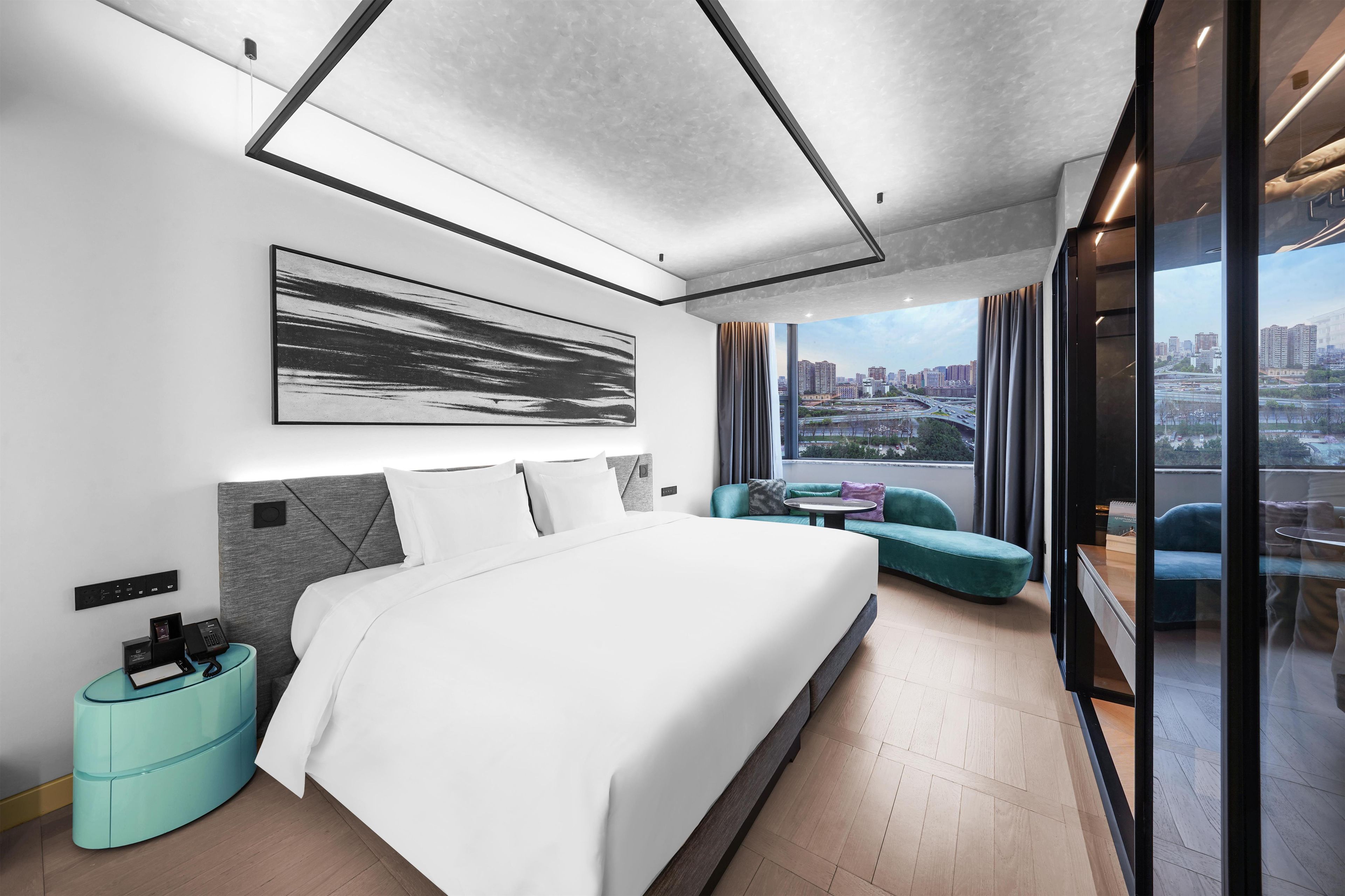 Una habitación de hotel moderna con una cama grande, vistas a la ciudad y un diseño contemporáneo.