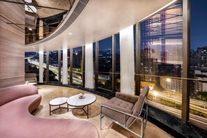 A modern interior with a curved ceiling, large windows offering a city view, and a seating area with a round table. - Kempinski Hotel Chengdu (Chengdu)