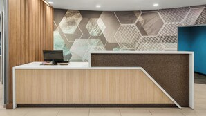A reception desk with a wooden finish, a computer, and a wall with geometric patterns. - Springhill Suites by Marriott Morgantown (Morgantown)