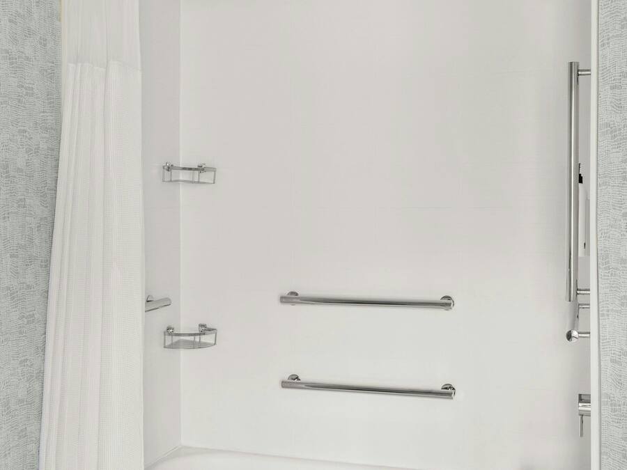A modern bathroom with a bathtub, shower, and a towel rack.