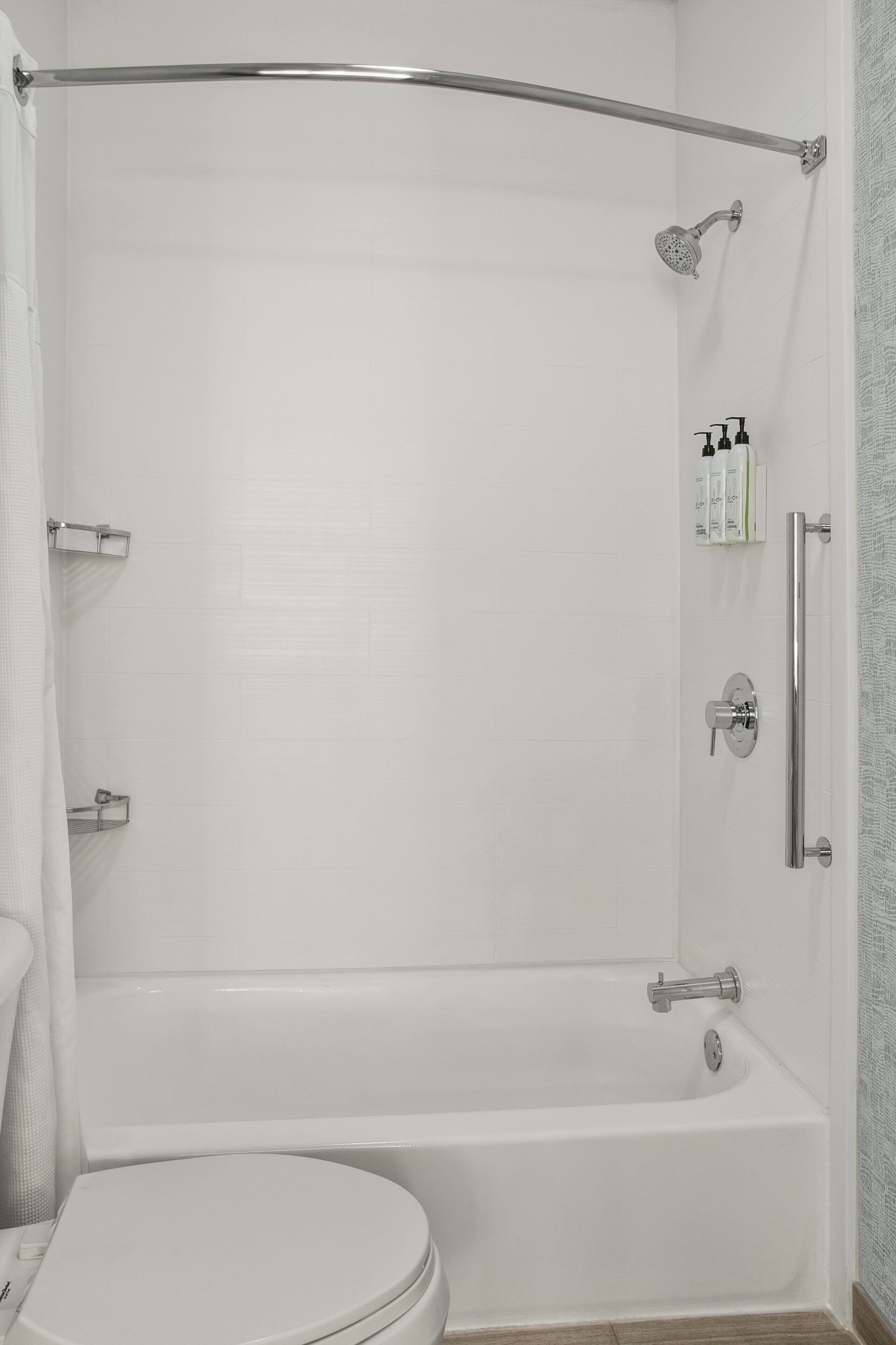 Un baño con bañera, inodoro, ducha y barras de apoyo.